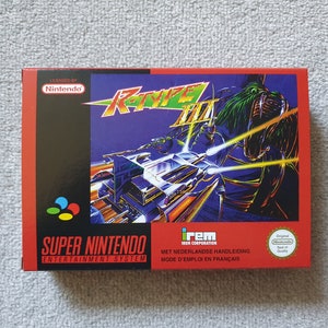 May include: R-Type III Super Nintendo game box. The box features a vibrant illustration of a spaceship in a futuristic setting. The box has the Super Nintendo Entertainment System logo and the Nintendo logo.