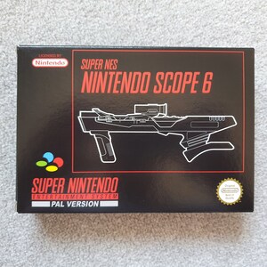 May include: A black rectangular box for the Super NES Nintendo Scope 6 video game accessory. The front features a white line drawing of the light gun, the red text Super NES Nintendo Scope 6, the Nintendo logo, and a gold seal of quality.