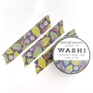 May include: A roll of washi tape with a floral design featuring green leaves, purple berries, and white flowers on a dark background. The tape is 15mm x 10m. Three strips of the same patterned tape are arranged nearby.