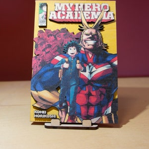 May include: Wooden My Hero Academia manga cover art. The artwork features the title, characters, and author's name. The base is a light brown color, and the artwork is in vibrant colors, including yellow, red, blue, and green.