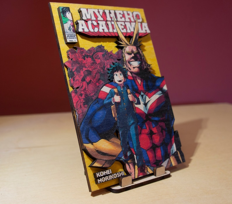 May include: Wooden My Hero Academia artwork featuring Deku and All Might. The artwork has a yellow background with the title "My Hero Academia" in red and white. The artist's name, Kohei Horikoshi, is also visible.