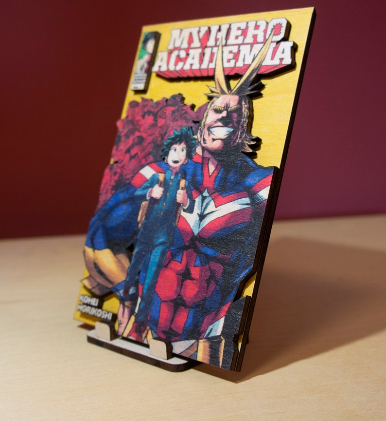 May include: Wooden artwork featuring a vibrant illustration from "My Hero Academia." The image showcases All Might and Deku, with the series title prominently displayed. The artwork is mounted on a wooden base, creating a 3D effect.