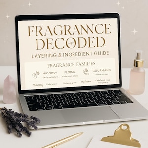 Może przedstawiać: Laptop wyświetla "FRAGRANCE DECODED" z przewodnikiem po warstwach i składnikach. Ekran pokazuje rodziny zapachów: Drzewne, Kwiatowe i Gourmand. Złoty długopis, różowy kryształ, gałązka lawendy i butelka perfum znajdują się na stole.