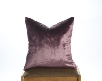 May include: A plush purple velvet cushion sits on a wooden chair with a brown fabric seat.