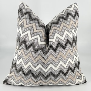 May include: A decorative throw pillow with a black, white, and beige chevron pattern.