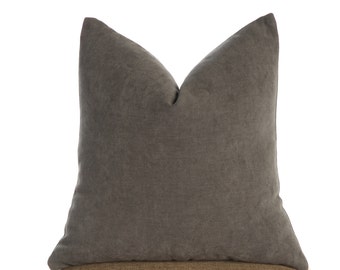 May include: A dark gray throw pillow with a soft, textured fabric. The pillow is sitting on a wooden chair with a brown fabric seat.