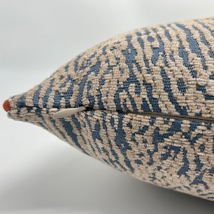 May include: Close-up of a blue and beige patterned throw pillow with a zipper closure.