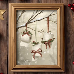 Puede incluir: Una impresión enmarcada representa rollos de papel higiénico adornados con lazos festivos y vegetación, colgados de ramas de árboles. La obra de arte tiene un fondo invernal y nevado, y está enmarcada en un marco dorado. Tema navideño.
