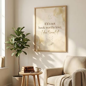 Pu&ograve; includere: Una stampa incorniciata con la citazione: "Se non &egrave; amore degno di un libro, non lo voglio." L'opera presenta uno sfondo beige con accenti simili ad acquerelli e una semplice illustrazione di un libro e pagine volanti. La cornice &egrave; in legno chiaro.