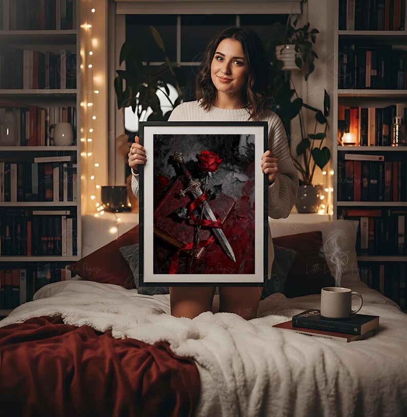 Puede incluir: Una obra de arte enmarcada con una rosa roja, una daga y un libro. La obra tiene un tema g&oacute;tico oscuro con tonos rojos y grises. El marco es negro.