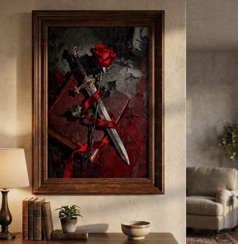 Puede incluir: Una obra de arte enmarcada que presenta una rosa roja, una daga y un libro. La rosa se coloca encima de la daga, con una cinta roja que los envuelve. El fondo es una mezcla de tonos rojo oscuro y gris, creando un efecto dram&aacute;tico. El marco es de madera marr&oacute;n.