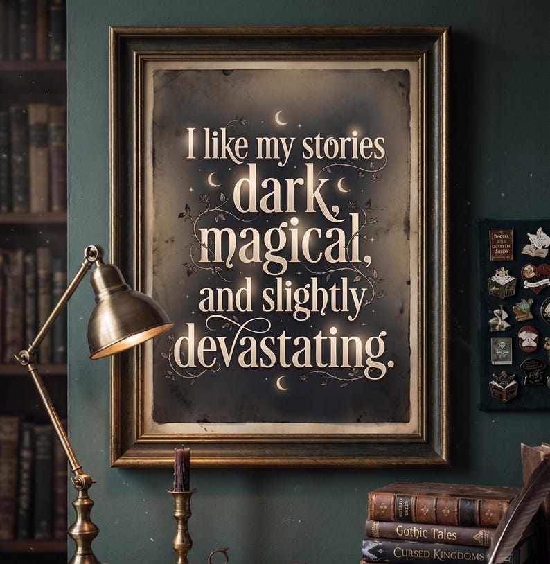 Op de afbeelding: Een ingelijste print met de tekst "I like my stories dark, magical, and slightly devastating." De tekst is wit op een donkere achtergrond, met een goudkleurige lijst. De afbeelding toont een bureaulamp en boeken.