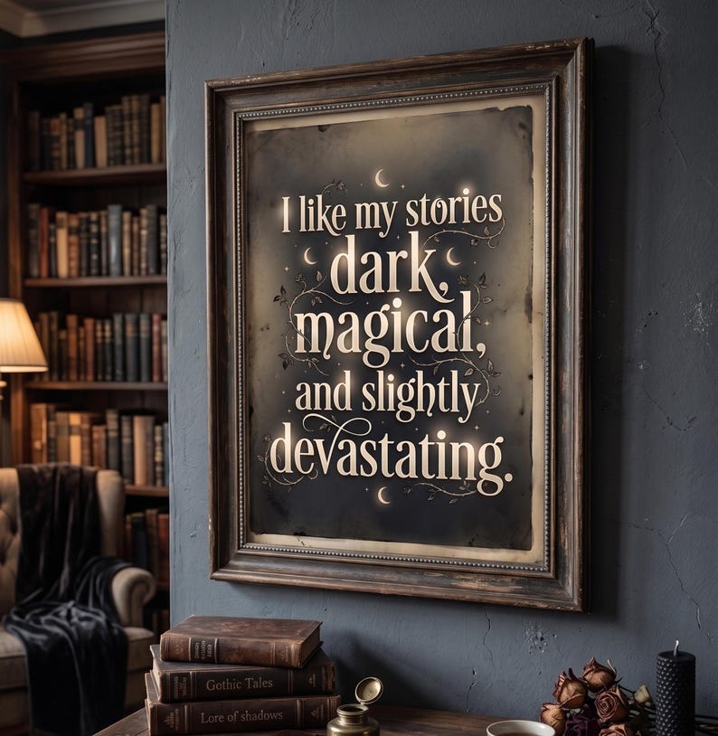 Op de afbeelding: Een ingelijste print met de tekst "I like my stories dark, magical, and slightly devastating." De print heeft een donkere achtergrond met witte letters en een decoratieve rand. De lijst is donkerbruin van kleur. De print hangt aan een donkerblauwe muur.