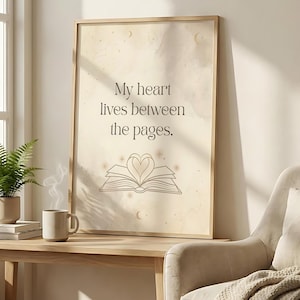 Pu&ograve; includere: Stampa incorniciata con la scritta "My heart lives between the pages". L'opera presenta un libro aperto stilizzato con un design a forma di cuore al centro. Lo sfondo ha una texture morbida, simile all'acquerello, con accenti celesti.