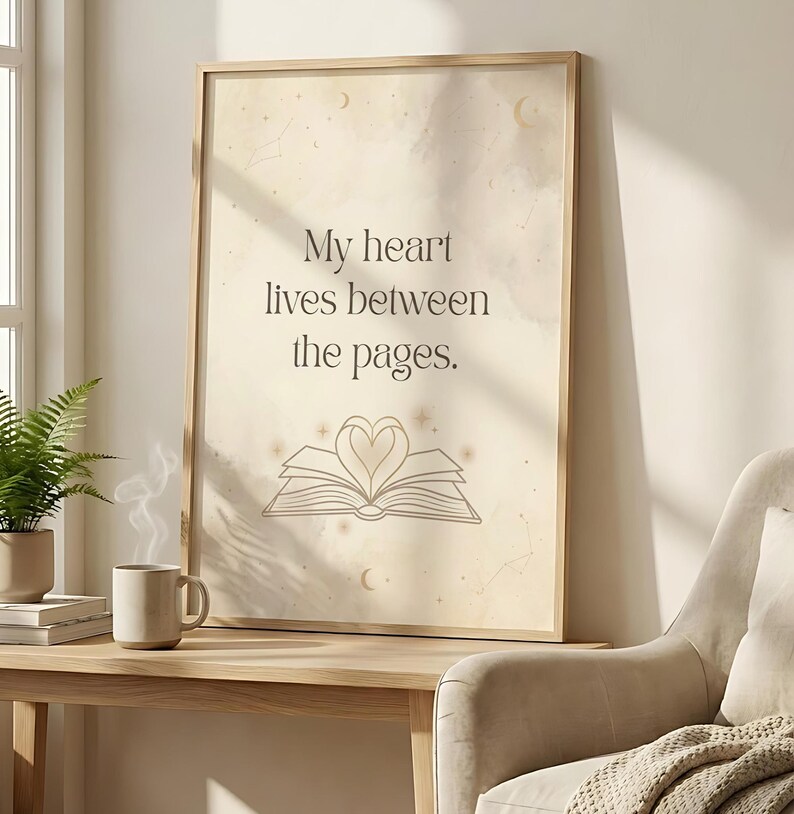 Pu&ograve; includere: Stampa incorniciata con la scritta "My heart lives between the pages". L'opera presenta un libro aperto stilizzato con un design a forma di cuore al centro. Lo sfondo ha una texture morbida, simile all'acquerello, con accenti celesti.