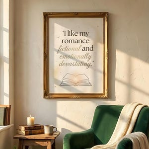 May include: A framed print with the quote, "I like my romance fictional and emotionally devastating." The print is in a gold ornate frame, with an illustration of an open book. The print hangs above a green armchair.