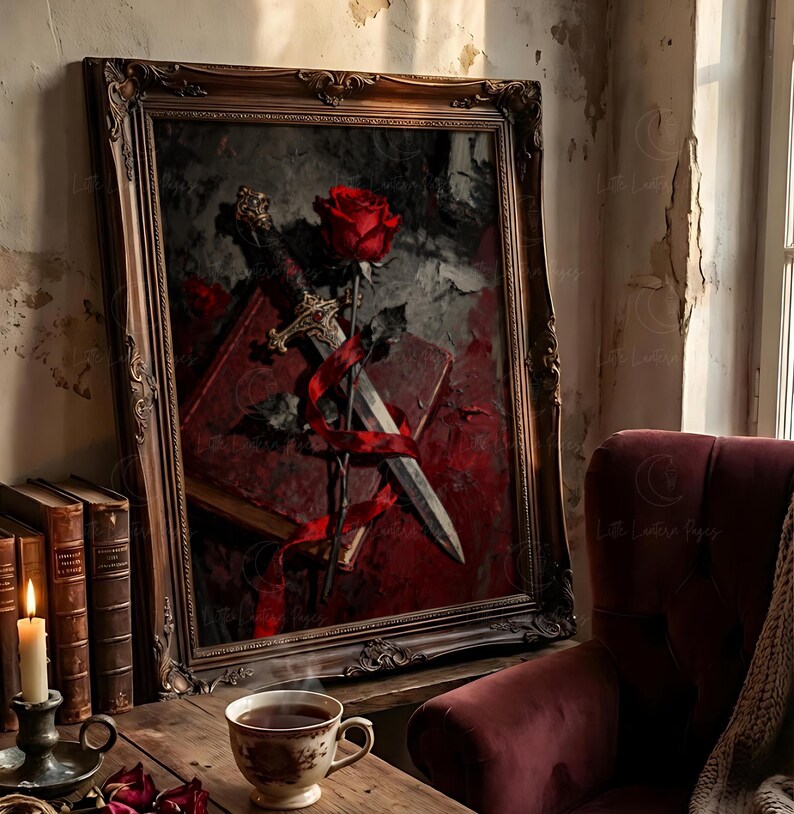 Puede incluir: Una obra de arte enmarcada con una rosa roja, una espada y un libro, todo entrelazado con una cinta roja. La obra de arte es de estilo oscuro y g&oacute;tico, con un marco de madera vintage. Una taza de t&eacute; y libros est&aacute;n sobre una mesa de madera.