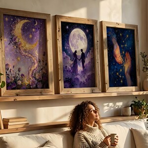 May include: Three framed art prints with celestial themes. One features a crescent moon with floral accents, another a couple under a full moon, and the third, hands reaching towards each other against a starry background. The frames are made of light-colored wood.