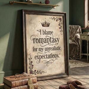 May include: Framed print with the quote "I blame romantasy for my unrealistic expectations." The print has a vintage map background, a crown, and floral accents. The frame is dark brown. The print is leaning against a green wall.
