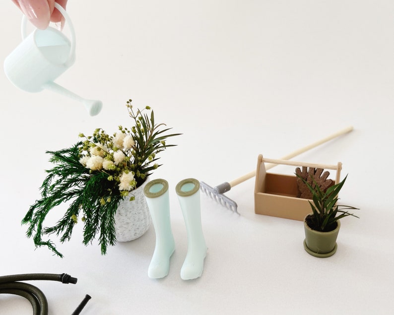 Miniature watering can in pale blue color. Features a long spout and round handle. Perfect for miniature garden or greenhouse scene.