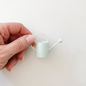 Miniature watering can in pale blue color. Features a long spout and round handle. Perfect for miniature garden or greenhouse scene.