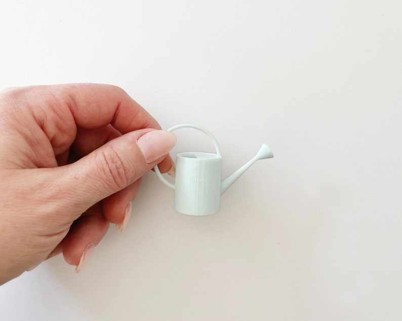 Miniature watering can in pale blue color. Features a long spout and round handle. Perfect for miniature garden or greenhouse scene.