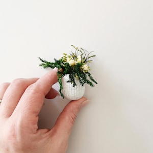 Miniature potted plant made from 100% natural preserved flowers and greenery. White flowers surrounded by green foliage in a stone textured pot.