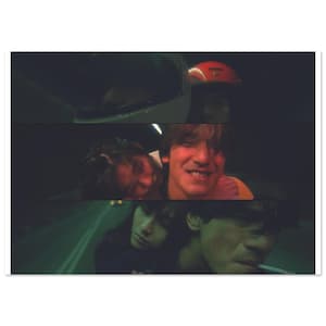 May include: A close-up shot of three people, two men and one woman, in a dimly lit setting. The woman is leaning against the man in the middle, who is smiling. The man on the right is looking at the camera and has a cigarette in his mouth.