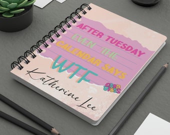 Könnte beinhalten: Rosa Notizbuch mit Spiralbindung mit dem Text "Nach Dienstag sagt sogar der Kalender WTF" und dem Namen "Katherine Lee" auf der Vorderseite. Das Notizbuch hat einen Aufkleber mit der Aufschrift "Good Vibes" in Regenbogenfarben.