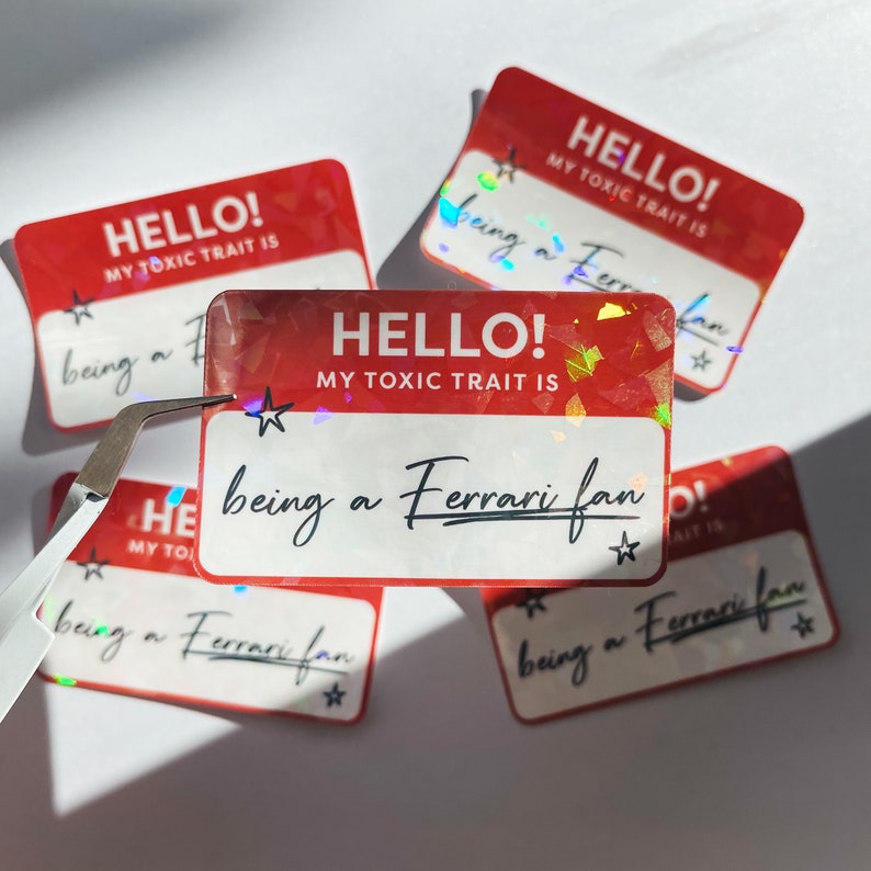 May include: Five red and white holographic stickers with the text "HELLO! MY TOXIC TRAIT IS being a Ferrari fan" on each. The stickers have a star on each side of the text.