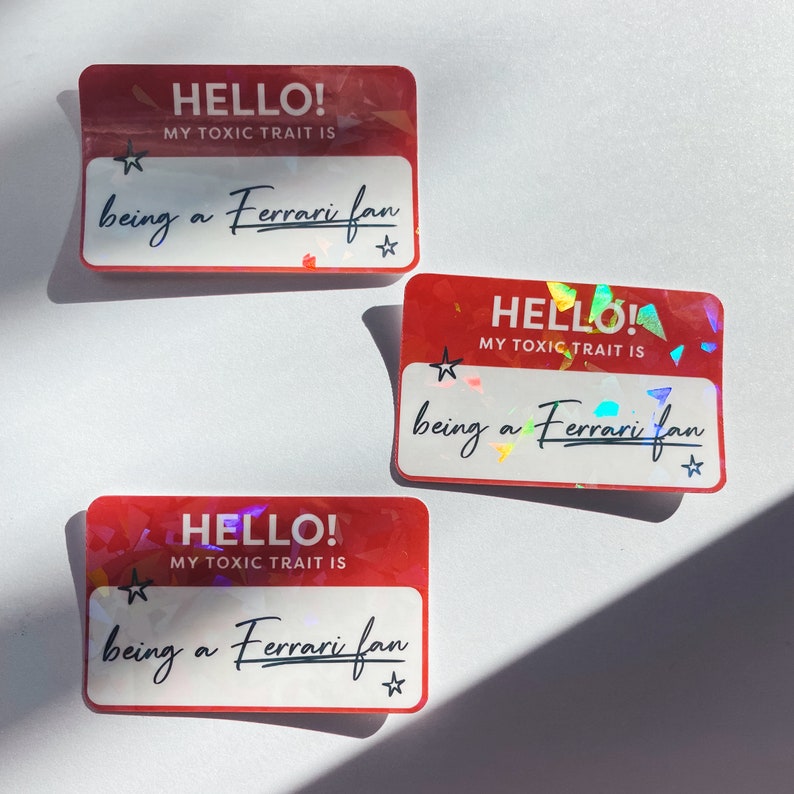 May include: Three red holographic stickers with the text "HELLO! MY TOXIC TRAIT IS being a Ferrari fan" on each.