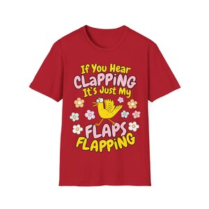 Może przedstawiać: Czerwona koszulka z napisem "If You Hear CLAPPING It's Just My FLAPS FLAPPING". Projekt zawiera ż&oacute;łtego ptaka i kolorowe kwiaty. Zabawna koszulka graficzna.