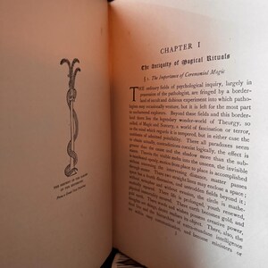 May include: An open book with text and an illustration of a serpent coiled around a staff. The page is from a book titled "The Serpent of the Rainbow" and discusses magical rituals.