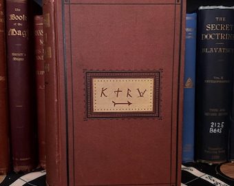 May include: A red hardcover book with a gold-colored rectangular label on the front cover. The label has the text "K+RW" and an arrow pointing to the right.