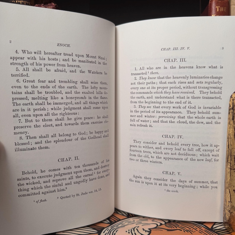 May include: Open book with text from the Book of Enoch, featuring chapters and verses. The pages are aged with visible text in black ink. The book is open to display the text.