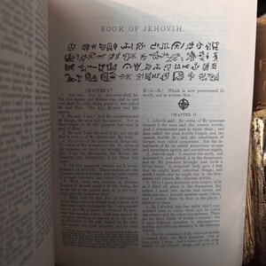 Pu&ograve; includere: Libro aperto con testo e simboli. Il titolo "BOOK OF JEHOVIH" &egrave; visibile in alto. Il testo &egrave; in inglese, con i titoli dei capitoli I e II. Le pagine sono ingiallite e invecchiate.