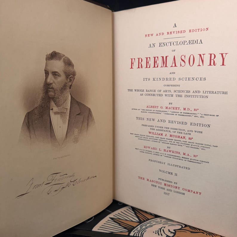 Puede incluir: Un libro abierto con una ilustraci&oacute;n detallada de un hombre en la p&aacute;gina izquierda y texto en la derecha. El texto dice "An Encyclopedia of Freemasonry" y "Volume II". Publicado por The Masonic History Company en 1917.