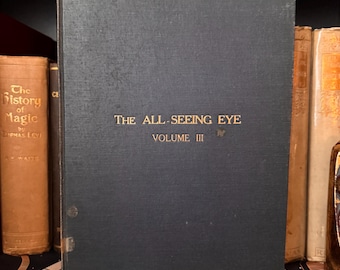 May include: A black hardback book with gold lettering on the spine. The title is "The All-Seeing Eye" and the volume number is "III".