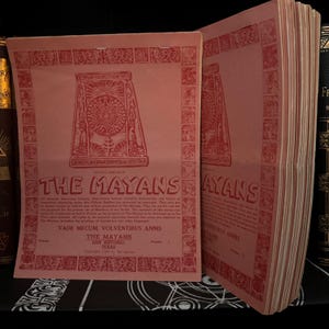 Könnte beinhalten: Ein Stapel alter roter Taschenbücher mit dem Titel "The Mayans" und einem dekorativen Rand. Das Cover zeigt ein rotes und weißes Symbol mit einem Kreis in der Mitte.