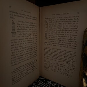 May include: A page from a book about the Egyptian god Osiris. The page features a black and white illustration of a hieroglyphic inscription and text that reads "Osiris Un-nefer and 1515". The text describes the god Osiris as the "avenger of his father" and the "judge of the dead".