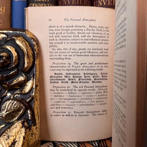 Puede incluir: Libro abierto con texto en una p&aacute;gina titulada "The Personal Atmosphere". La p&aacute;gina est&aacute; numerada 60. El libro est&aacute; rodeado de otros libros con cubiertas doradas y azules. El texto est&aacute; en tinta negra.