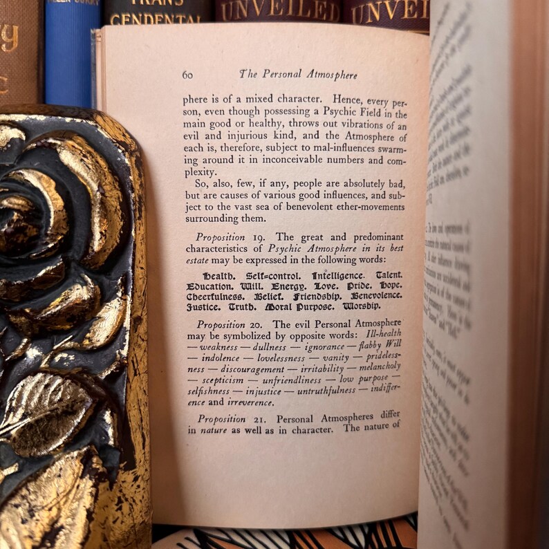 Puede incluir: Libro abierto con texto en una p&aacute;gina titulada "The Personal Atmosphere". La p&aacute;gina est&aacute; numerada 60. El libro est&aacute; rodeado de otros libros con cubiertas doradas y azules. El texto est&aacute; en tinta negra.