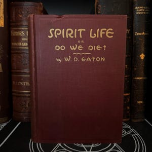 May include: A burgundy hardcover book with gold lettering on the spine and front cover. The title is "Spirit Life or Do We Die?" by W.D. Eaton.
