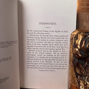 May include: Open book with the title "Introduction" and text from the Epistle of Jude. A decorative gold-colored object is visible on the right side of the image. The book is from Wizards Bookshelf, San Diego, USA.