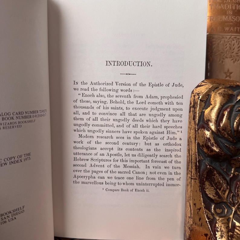 May include: Open book with the title "Introduction" and text from the Epistle of Jude. A decorative gold-colored object is visible on the right side of the image. The book is from Wizards Bookshelf, San Diego, USA.