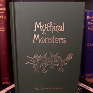May include: A green hardback book with the title "Mythical Monsters" in gold lettering. A gold illustration of a dragon is on the front cover.