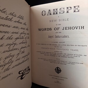 Pu&ograve; includere: Libro aperto con il titolo "OAHSPE" in grandi lettere ornate. Il testo recita "Una nuova Bibbia nelle parole di Jehovih e dei suoi ambasciatori angelici". Le pagine del libro sono invecchiate con testo in inchiostro nero.