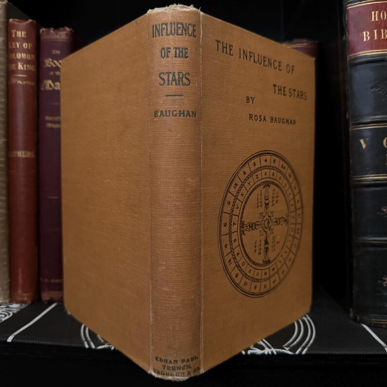 May include: A brown book titled "The Influence of the Stars" by Rosa Baughan. The book cover features a circular diagram with numbers and symbols.