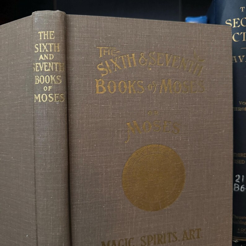 May include: The Sixth & Seventh Books of Moses on Magic Spirits. Art. A brown book with gold lettering and a gold circle with a design inside.