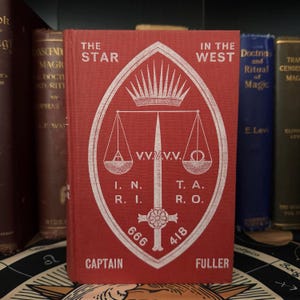 Pu&ograve; includere: Un libro rosso con un simbolo bianco sulla copertina. Il simbolo &egrave; uno scudo con una spada, una bilancia e una corona. Il titolo del libro &egrave; "The Star in the West".